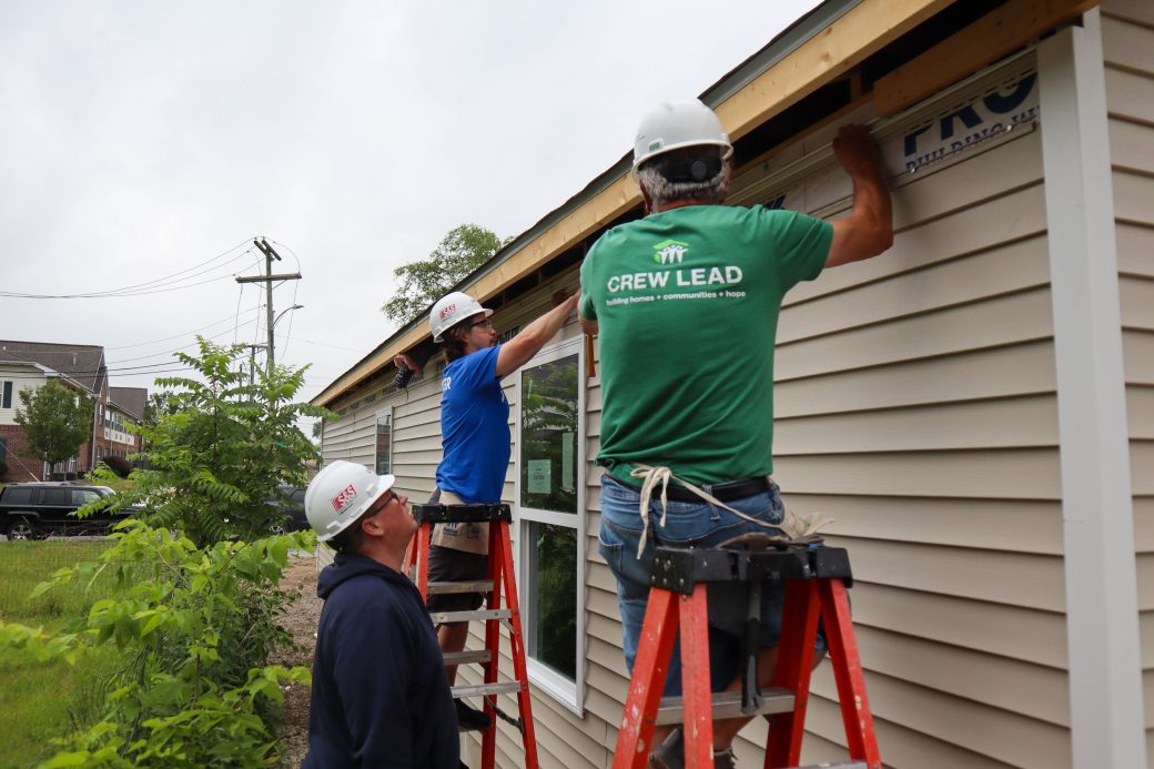 Crew lead helping volunteers install siding