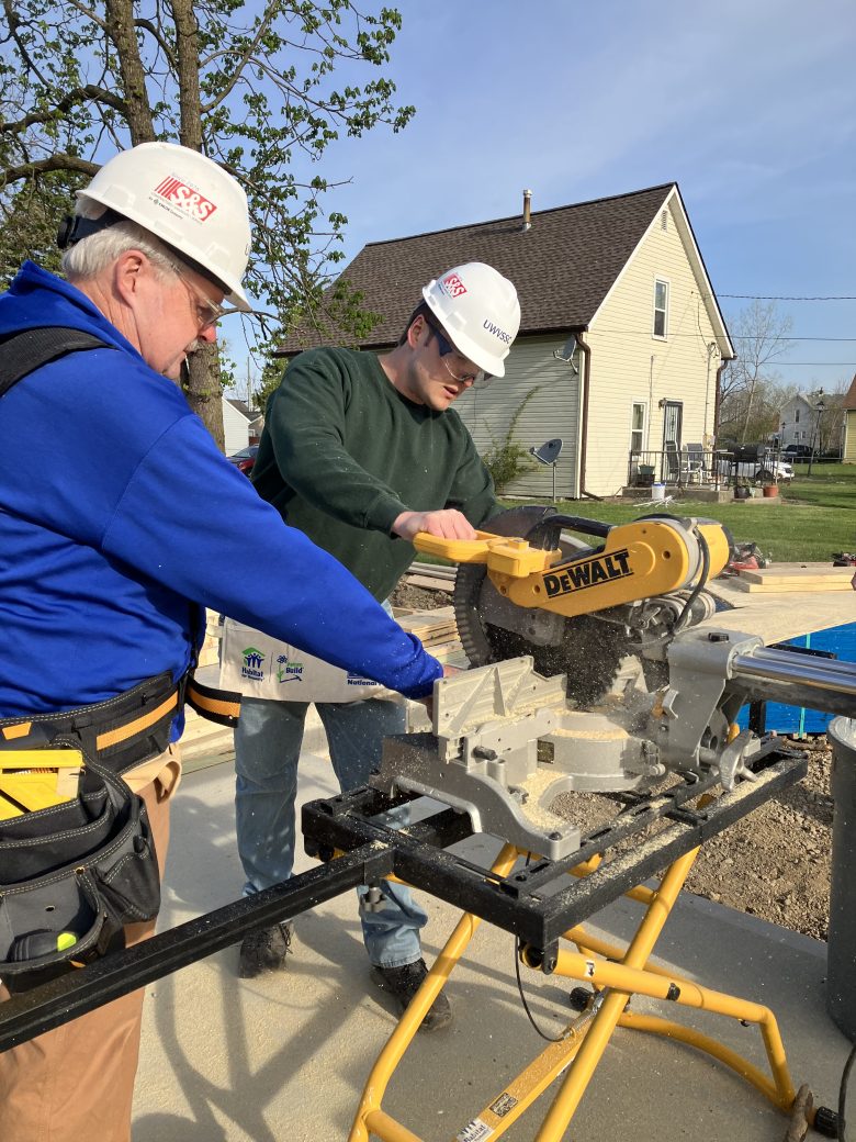 Crew lead assisting volunteer with saw
