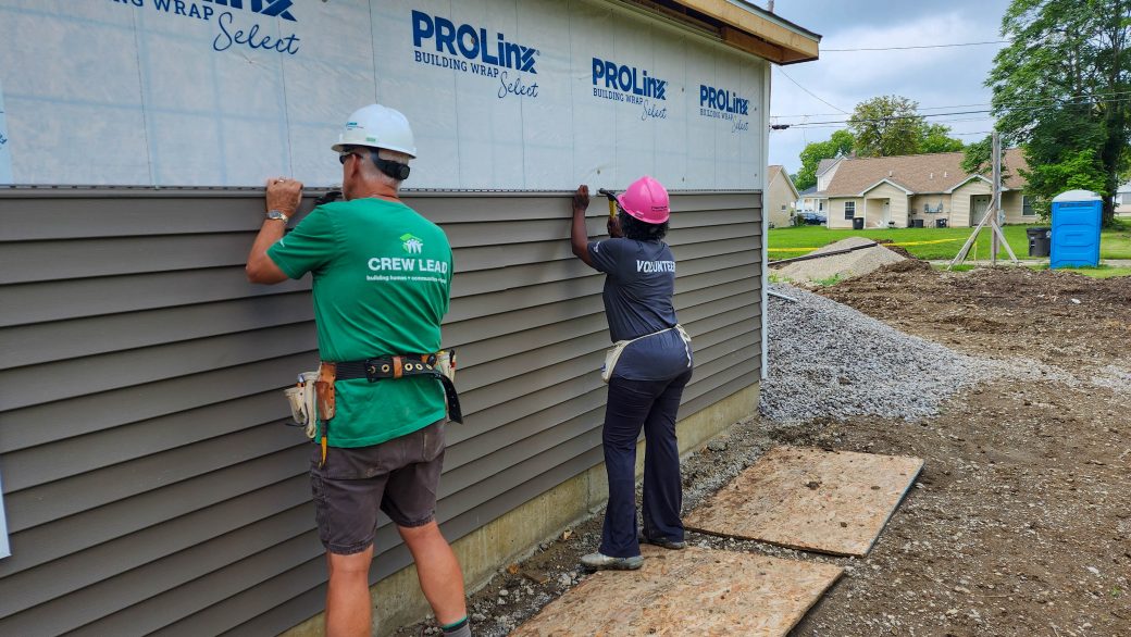 Crew lead and volunteer installing siding