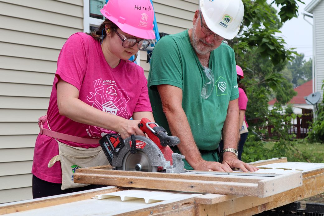 Crew lead helping volunteer with saw