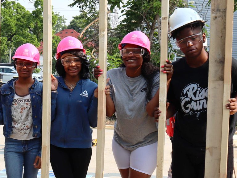 Ciaira and family holding up first wall of their home