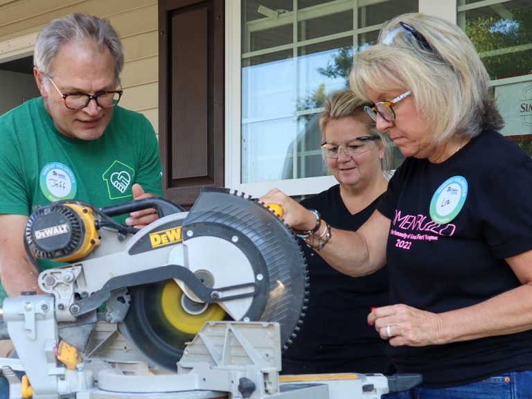 Crew lead teaching two volunteers on saw