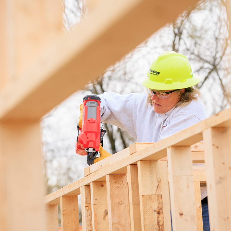 Woman nailing walls of home