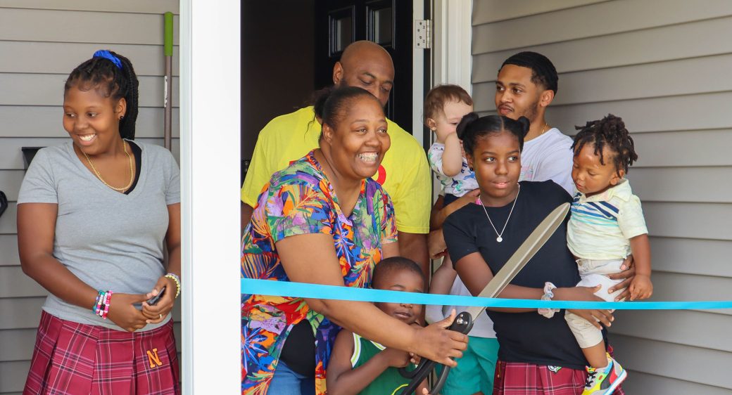 Family cutting ribbon at home dedication