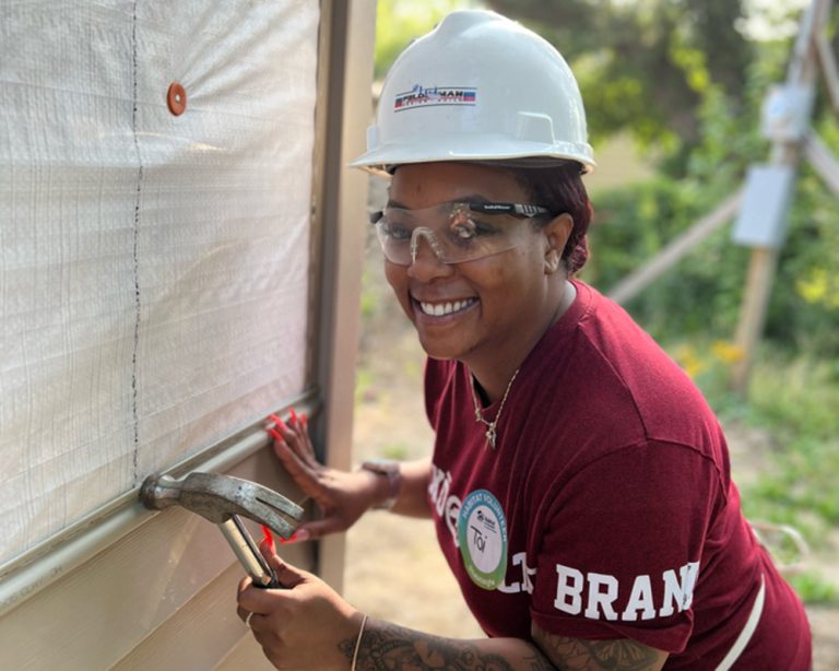 Volunteer in hardhat using hammer