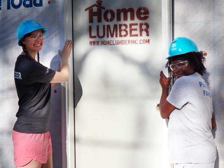 Habitat homeowner and volunteer smiling wearing hard hats