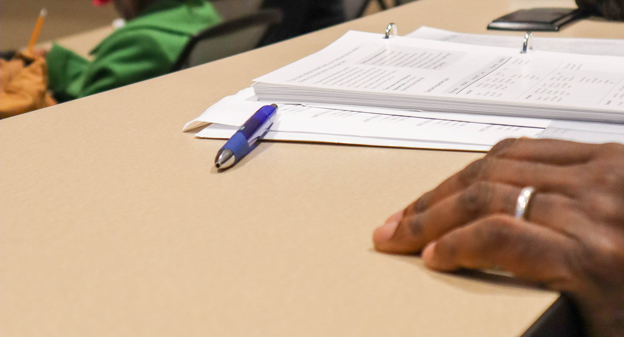 Hand next to pen and paper on table