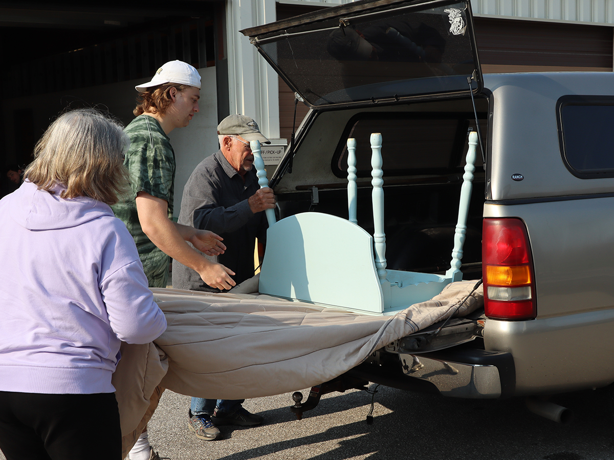 People removing table from truck bed